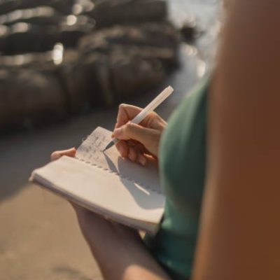 Young woman writes on notepad at beach